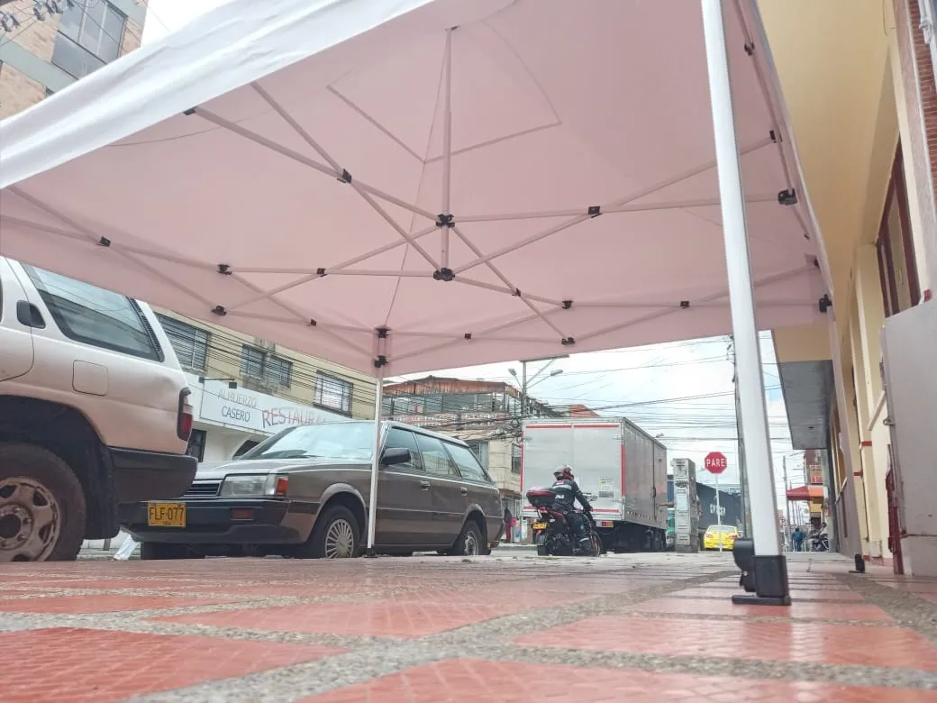 Carpa tipo kiosco blanca cubriendo el andén frente a un local comercial