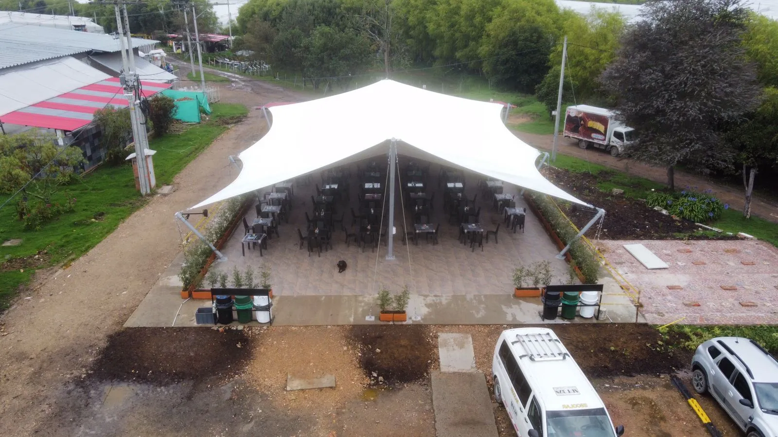Tenso-estructura blanca de dos picos cubriendo una zona de eventos con sillas