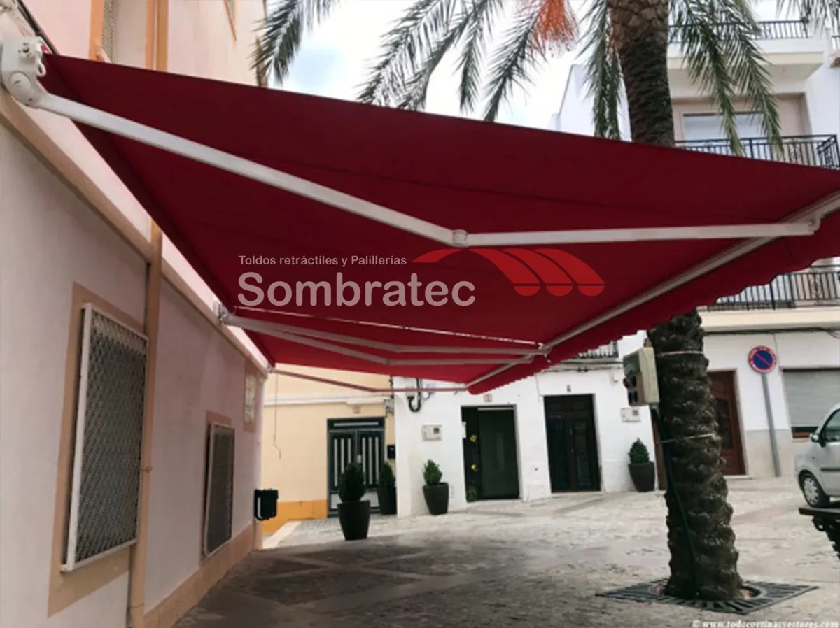 Toldo retráctil vinotinto instalado en la fachada de una casa