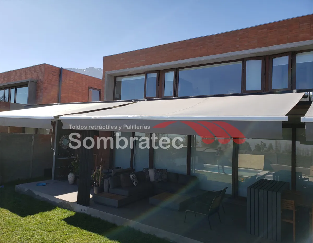 Toldo retráctil beige cubriendo la terraza de un edificio en ladrillo