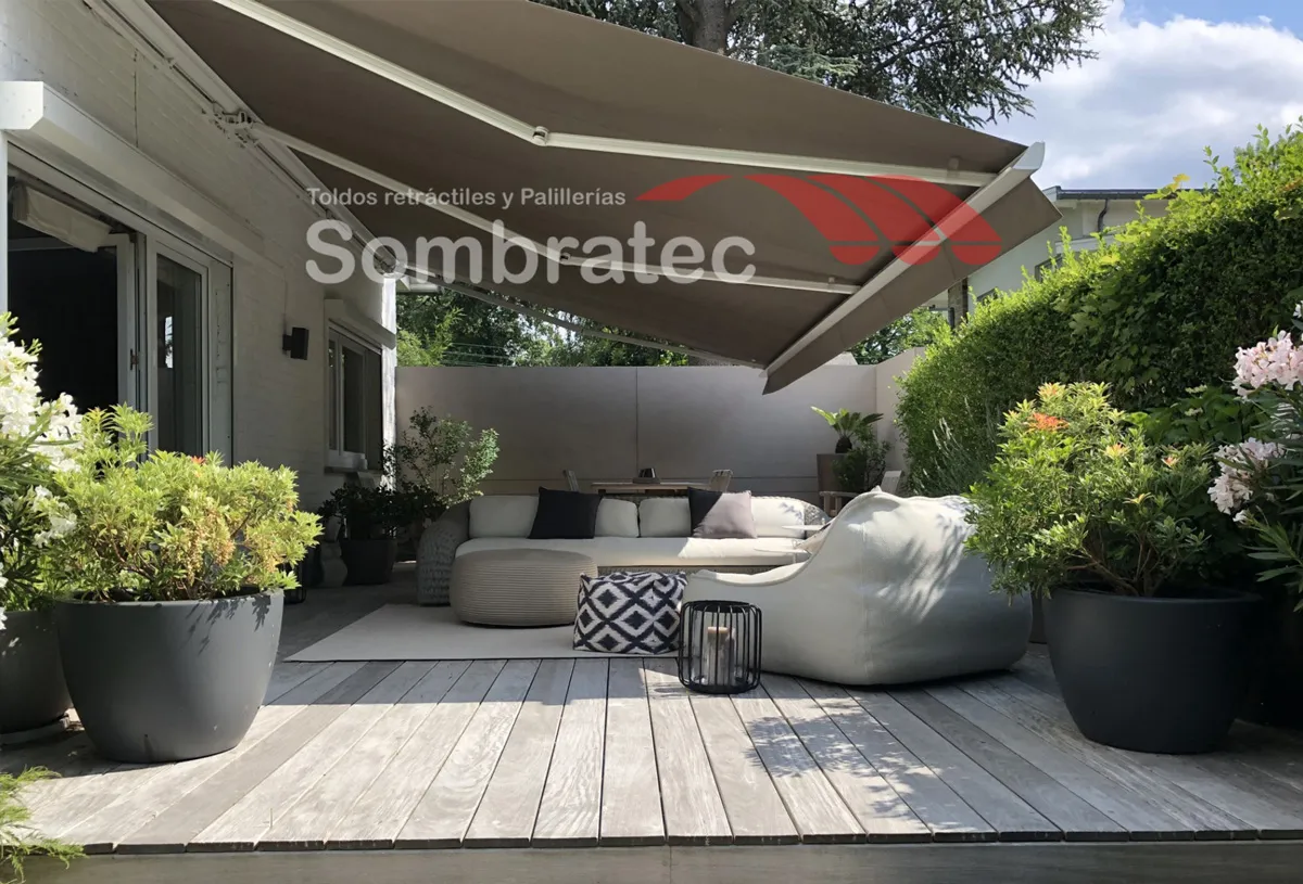 Toldo retráctil gris sobre un deck de madera con sala de exteriores