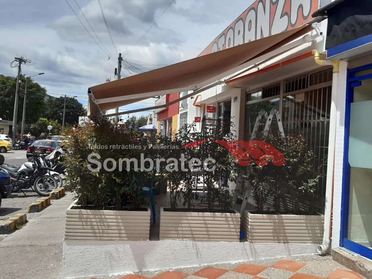 Toldo retráctil marrón sobre la entrada de un local comercial