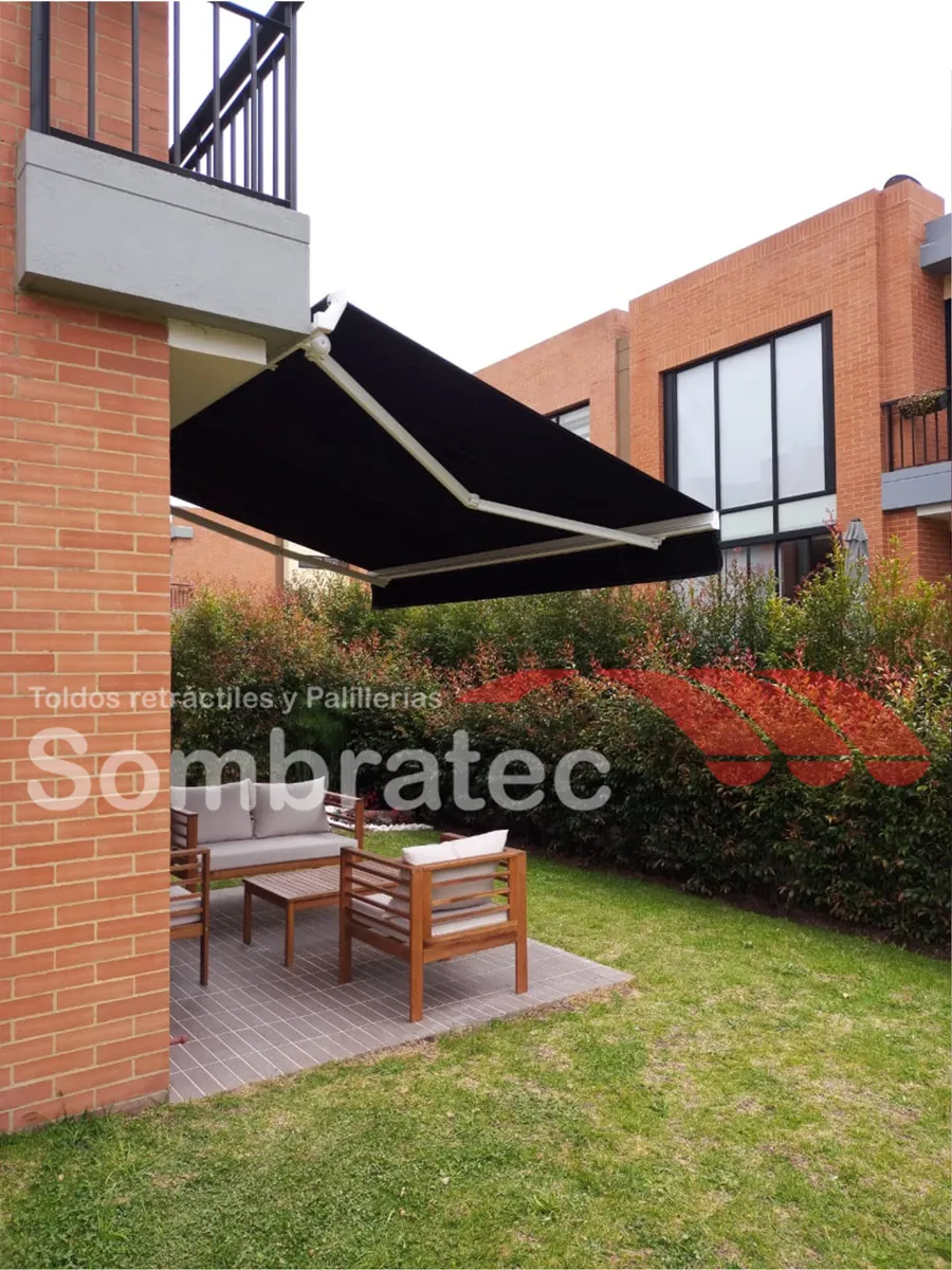 Toldo retráctil negro dando sombra a un patio con banca de madera