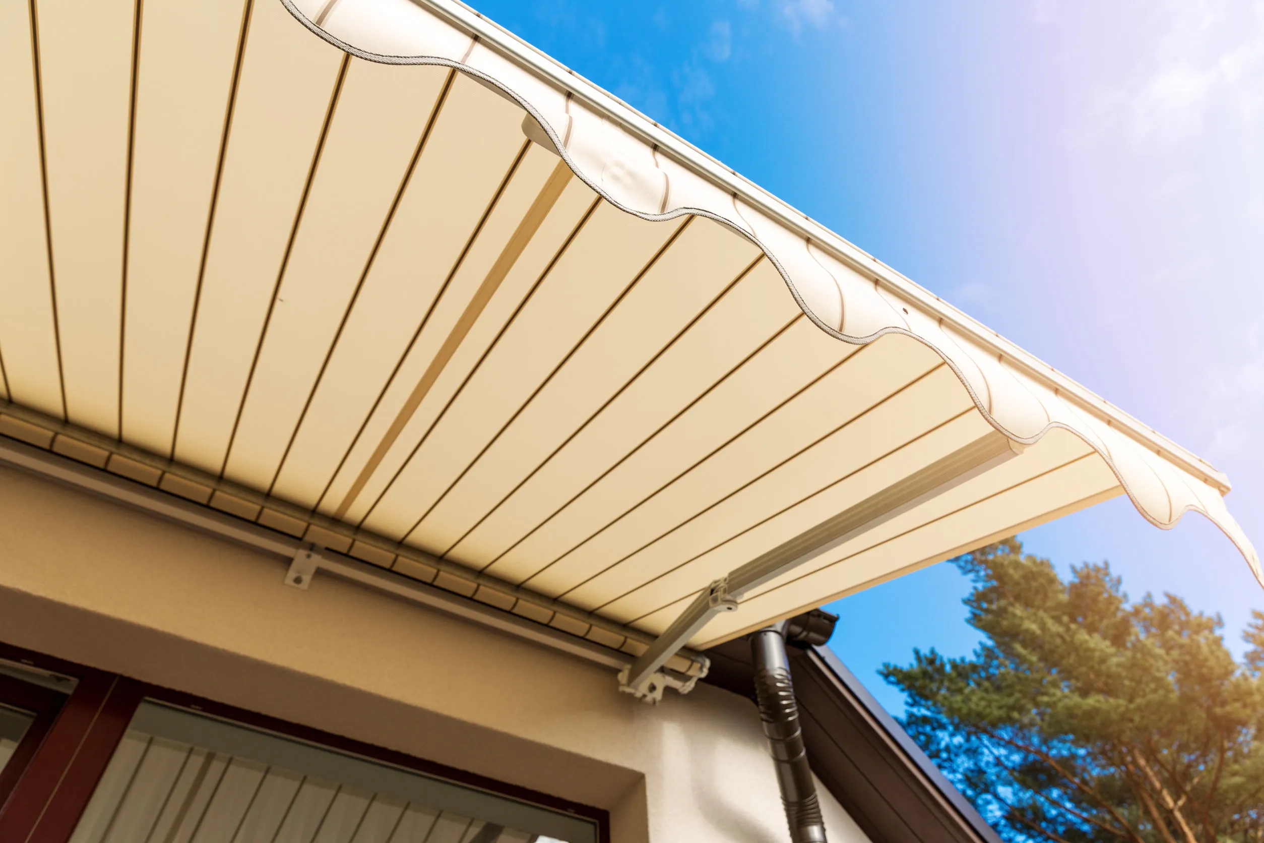 Toldo retráctil beige extendido visto desde abajo contra el cielo